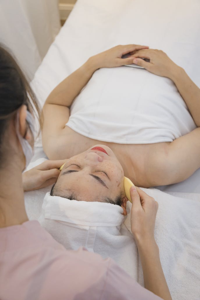 Woman receiving a soothing facial treatment at a spa, lying relaxed with eyes closed.